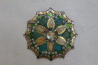 Photo of a mosaic flower on a wall, in green, gold and white colors