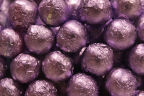 Photo of a close-up of spherical candy wrapped in lavender foil arranged in a lattice 