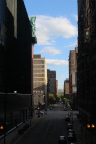 Photo of a street with dark buildings on either side and tall buildings in the background