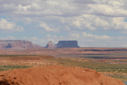 Photo of an orange boulder in the foregound and several buttes in the far background