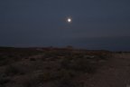 Photo of the moon over a darkened southwestern landscape