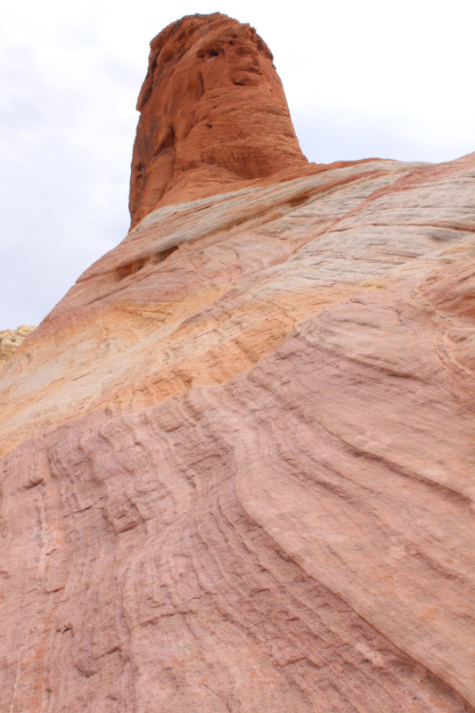 Photo of a red sedimentary rock stretching up to a large red hoodoo