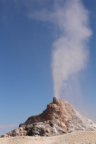 Photo of a smoking built up gray and brown geyser