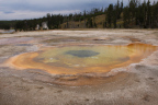 Photo of a hot spring showing the brown and green rings around the dark center